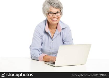 Happy elderly woman working in the office with a laptop