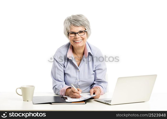 Happy elderly woman working in the office with a laptop