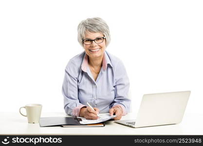 Happy elderly woman working in the office with a laptop