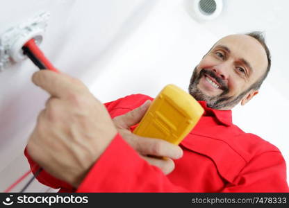 happy electrician checking voltage in electrical wall socket