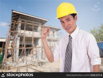 Happy engineer celebrating with arm raised, concept of successful, house construction background