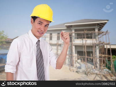 Happy engineer celebrating with arm raised, concept of successful, house construction background