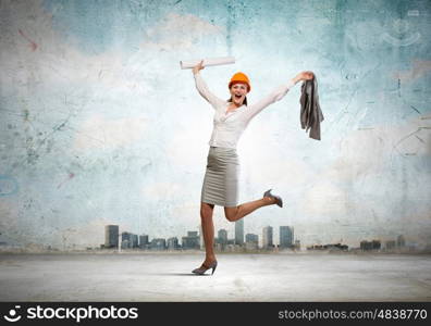 Happy engineer. Young woman engineer in helmet jumping joyfully