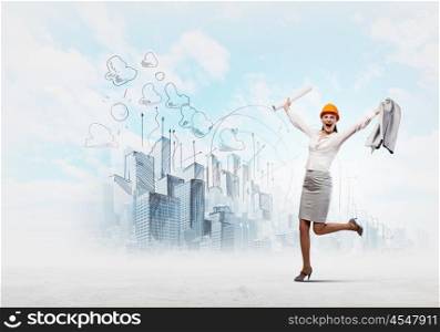 Happy engineer. Young woman engineer in helmet with project in hand jumping joyfully