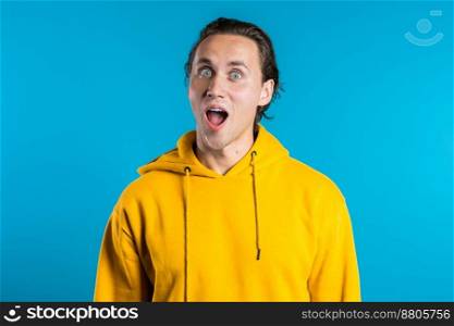 Happy european man rejoices with amazement. Handsome guy with stylish hairdo surprised to camera over blue background. High quality photo. Happy european man rejoices with amazement. Handsome guy with stylish hairdo surprised to camera over blue background.