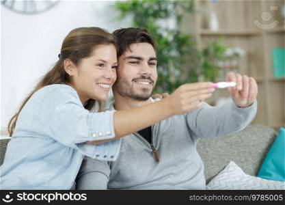 happy excited couple making positive pregnancy test and celebrating