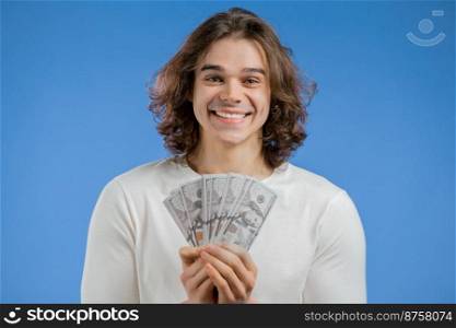 Happy excited man with cash money - USD currency dollars banknotes on blue wall. Symbol of jackpot, gain, victory, winning the lottery. High quality photo. Happy excited man with cash money - USD currency dollars banknotes on blue wall. Symbol of jackpot, gain, victory, winning the lottery