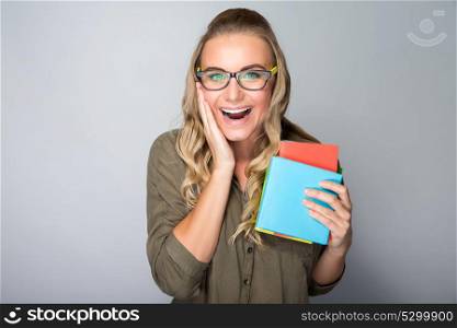 Happy excited student girl with surprised facial expression over gray background, enjoying first days in the university, getting high education