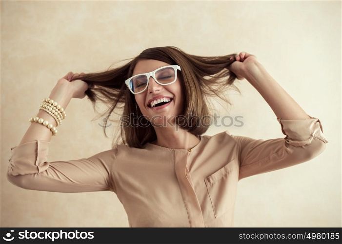 Happy excited woman dancing cheerful with wind in the hair on beige background