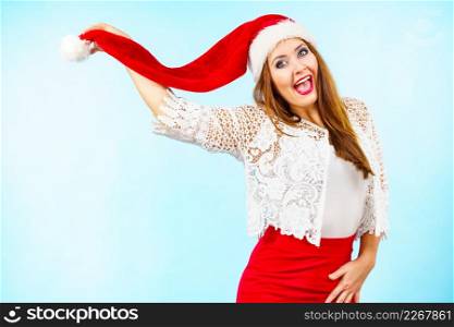 Happy excited young woman wearing santa claus red hat, on blue. Christmas holiday season.. Excited woman in christmas santa hat