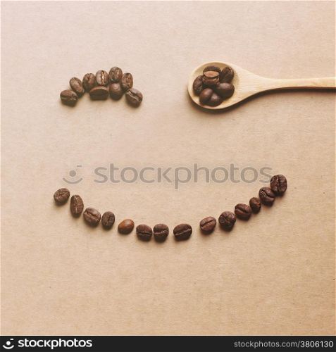 Happy face shaped of coffee beans with wooden spoon, retro filter effect