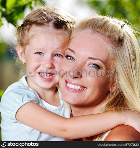 Happy faces of the young mother and little girl outdoor