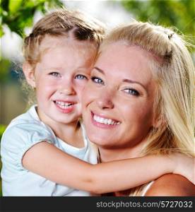 Happy faces of the young mother and little girl outdoor