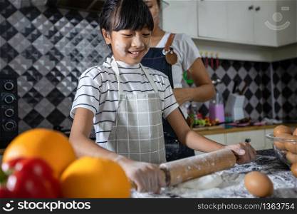 Happy Family and their little daughter preparing a pizza, knead the dough and puts ingredients on kitchen table