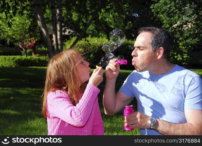 Happy family blowing soap bubbles, father and child