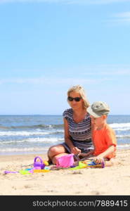 Happy family child son and mother playing toys on beach sea background