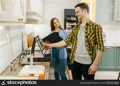 Happy family couple in furniture store. Man and woman looking table top pattern in shop, husband and wife buys goods for modern home interior. Happy family couple in furniture store