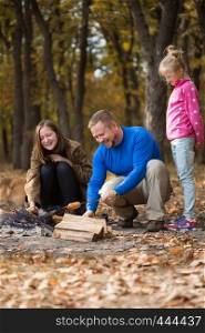 Happy family - dad with daughters on picnic in the autumn forest