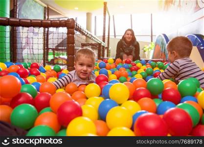 happy family enjoying free time young mom playing with kids in pool with colorful balls at childrens playroom