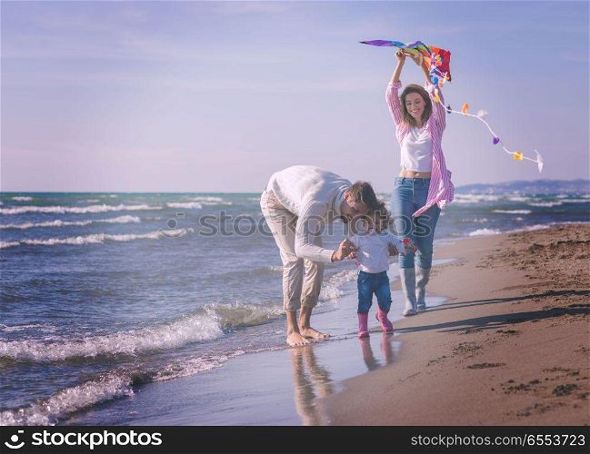 happy family enjoying vecation during autumn day. Family with little daughter resting and having fun with a kite at beach during autumn day colored filter
