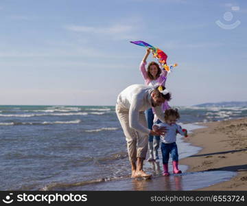 happy family enjoying vecation during autumn day. Family with little daughter resting and having fun with a kite at beach during autumn day