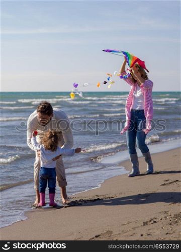 happy family enjoying vecation during autumn day. Family with little daughter resting and having fun with a kite at beach during autumn day
