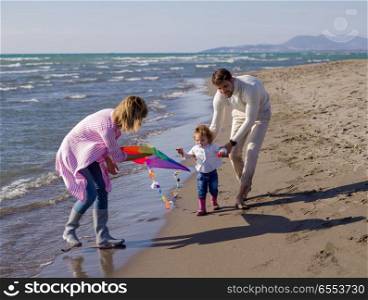 happy family enjoying vecation during autumn day. Family with little daughter resting and having fun with a kite at beach during autumn day