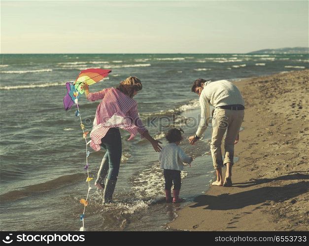 happy family enjoying vecation during autumn day. Family with little daughter resting and having fun with a kite at beach during autumn day colored filter