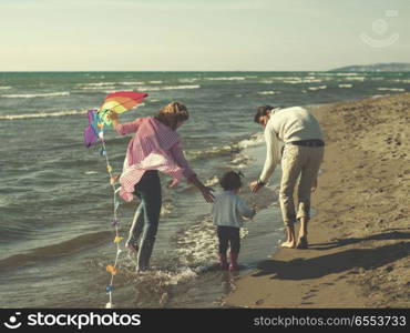 happy family enjoying vecation during autumn day. Family with little daughter resting and having fun with a kite at beach during autumn day colored filter