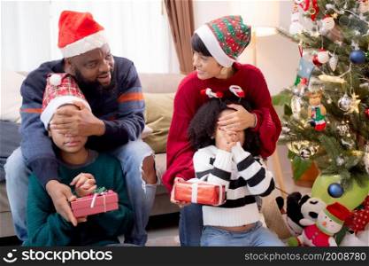 Happy family father and mother close eye daughter and giving gift box on celebration in Christmas day at home, xmas with parent surprising children at house, thanksgiving eve, Merry Christmas.