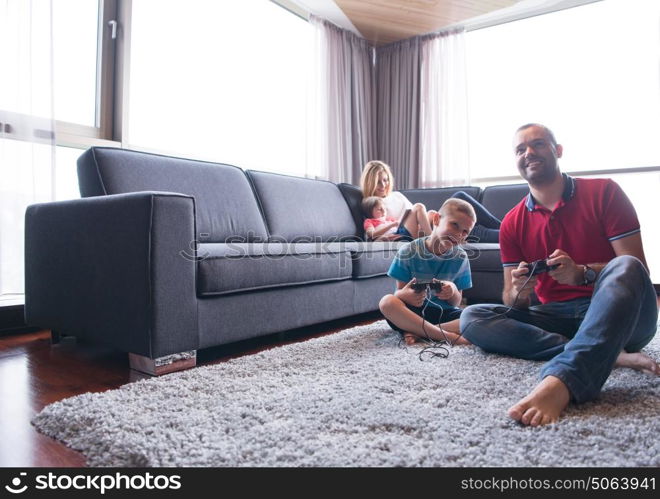 Happy family. Father, mother and children playing a video game Father and son playing video games together on the floor