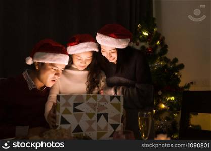 happy family, father mother daughter help to open gift present box together at christmas day night in dining room that decorated with christmas tree for christmas festival day