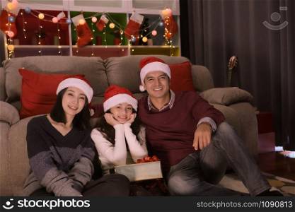 happy family, father, mother, daughter sitting together, they happy and smiling, celebrate at christmas day night in living room that decorated with christmas tree for christmas festival day