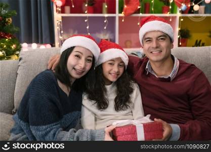 happy family, father mother give gift presents to daughter and celebrating together at christmas day night in living room that decorated with christmas tree for christmas festival day