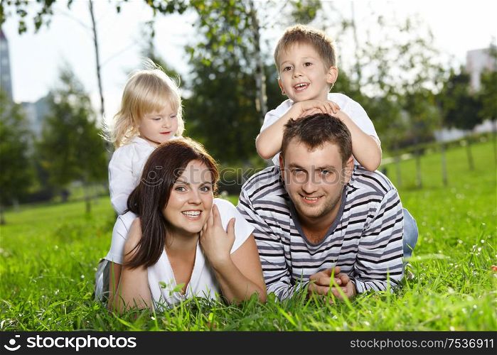 Happy family from four persons lies on a summer lawn