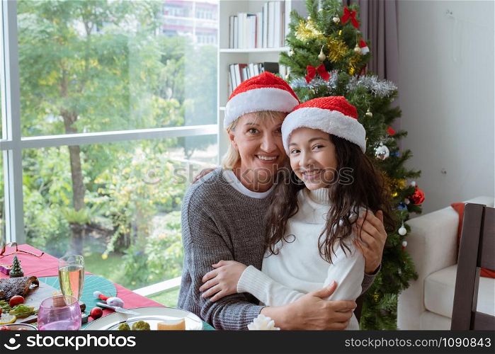happy family, grandmother smile and hug daughter little girl and celebrate together on christmas in dining room that decorated with christmas tree christmas festival day, happy family holiday concept