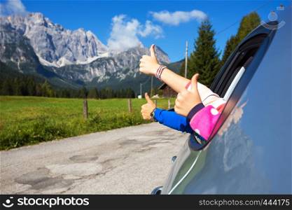 happy family - hands of men and children peering out of the car on a background of mountains. Dolomites, Italy.