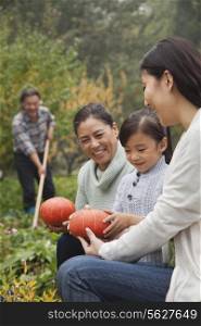 Happy family harvesting vegetables in garden