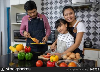 Happy Family have Dad, Mom and their little daughter Cooking Together in the Kitchen