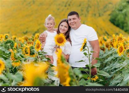 happy family having fun in the field of sunflowers. Mother holding her daughter and sunflower in hand. The concept of summer holiday. Mother&rsquo;s, father&rsquo;s, baby&rsquo;s day. Family spending time together.. happy family having fun in the field of sunflowers. Mother holding her daughter and sunflower in hand. The concept of summer holiday. Mother&rsquo;s, father&rsquo;s, baby&rsquo;s day. Family spending time together
