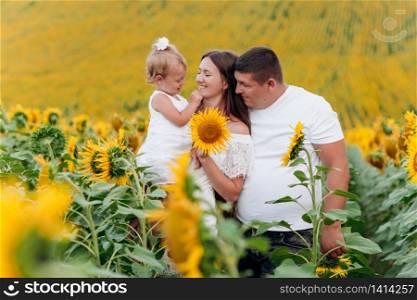 happy family having fun in the field of sunflowers. Father holding his daughter. Mother holding sunflower. outdoor shot. selective focus.. happy family having fun in the field of sunflowers. Father holding his daughter. Mother holding sunflower. outdoor shot. selective focus