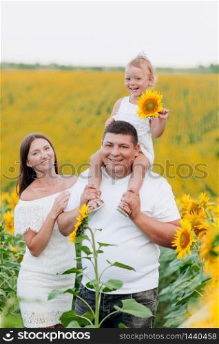 happy family having fun in the field of sunflowers. Father holding his daughter. Mother holding sunflower. outdoor shot. selective focus. happy family having fun in the field of sunflowers. Father holding his daughter. baby girl holding sunflower. outdoor shot. selective focus.