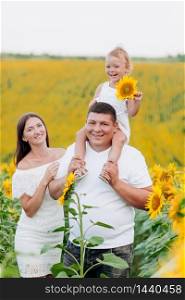 happy family having fun in the field of sunflowers. Father holding his daughter. Mother holding sunflower. outdoor shot. selective focus. happy family having fun in the field of sunflowers. Father holding his daughter. baby girl holding sunflower. outdoor shot. selective focus.