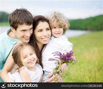 Happy family having fun outdoors in spring field against blurred grass and sky background