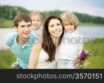 Happy family having fun outdoors in spring field against green background