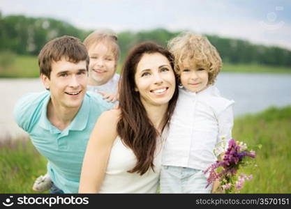 Happy family having fun outdoors in spring field against green background