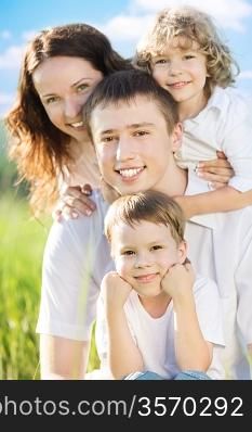 Happy family having fun outdoors in spring green field against blue sky background