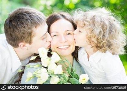 Happy family having fun outdoors in spring park against nature green background. Mother`s day concept