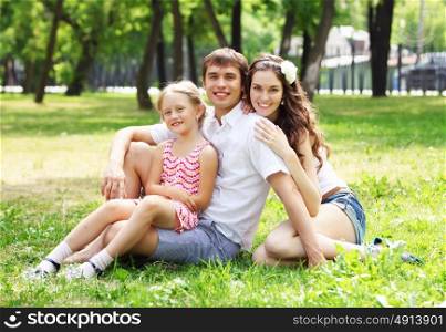 happy family having fun outdoors. Young Family Outdoors on the grass in Park in summer