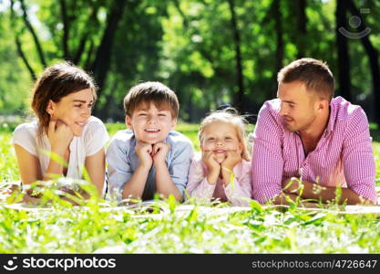 Happy family having weekend in summer park. Picnic in garden